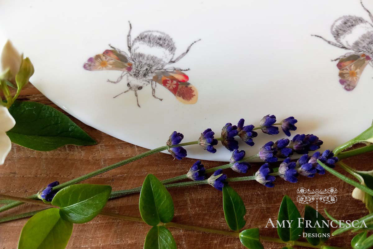 Decorative platter featuring bee illustrations, shown with lavender and flowers.