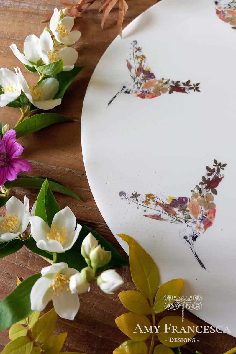 Serving platter featuring hummingbird illustrations, shown with surrounding flowers and leaves.