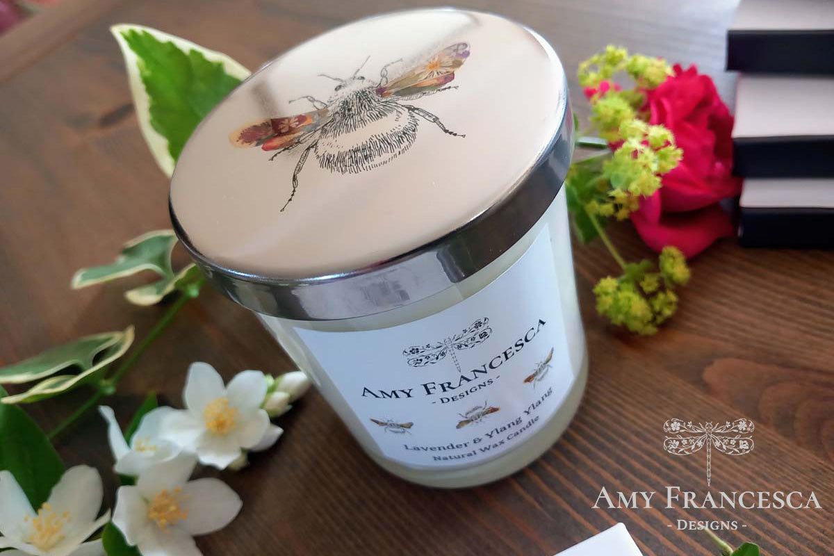 Candle featuring bee illustrations on both the lid and the jar label, shown with surrounding flowers.